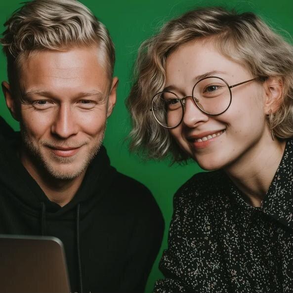 Kaksi työkaveria katsoo yhdessä kannettavan tietokoneen näyttöä ja hymyilee.